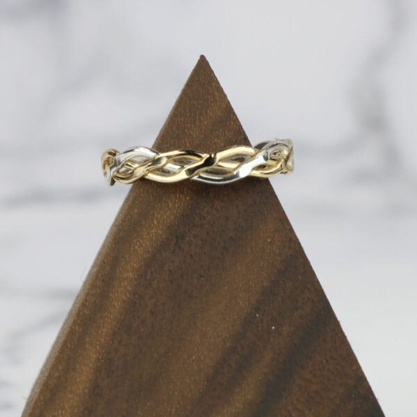 A Two Tone Eternity Knot Band on top of a pyramid.