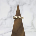A Two Tone Eternity Knot Band sitting on top of a wooden stand.
