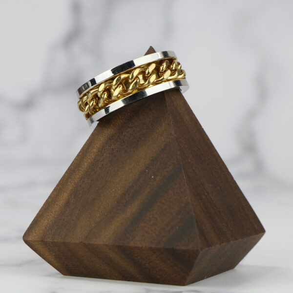 A Two Tone Celtic Braided Ring on a wooden stand.