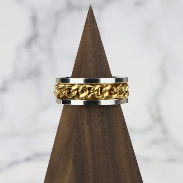 A Two Tone Celtic Braided Ring resting on a wooden base.