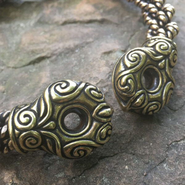 A pair of Chieftain's Torc Extra Heavy Braid brass beaded bracelets on a rock.