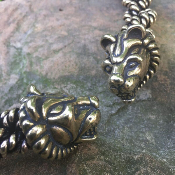A pair of Celtic Lion Torc - Extra Heavy Braid bracelets on a rock.