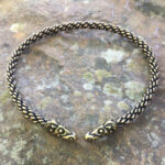 A Celtic Ram Torc - Medium Braid bracelet with two braided heads on top of a stone.