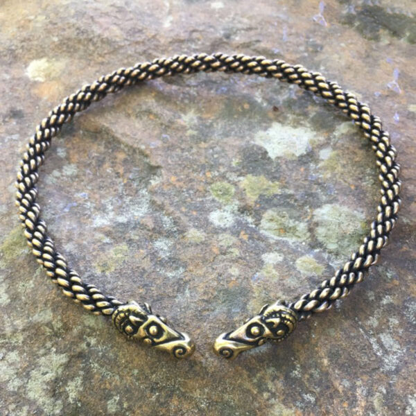 A Celtic Ram Torc - Medium Braid bracelet with two braided heads on top of a stone.