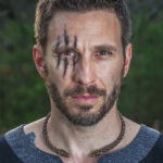 A man with a Celtic Raven Neck Torc on his face.