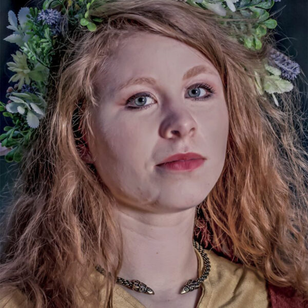 A young woman wearing a flower crown and a Celtic Raven Neck Torc.