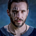 A man with a Celtic Spiral Torc - Medium Braid tattoo on his face.