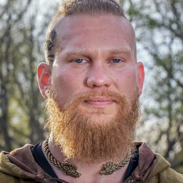 A man with a red beard is standing in the woods, adorned with a Celtic Stag Neck Torc.