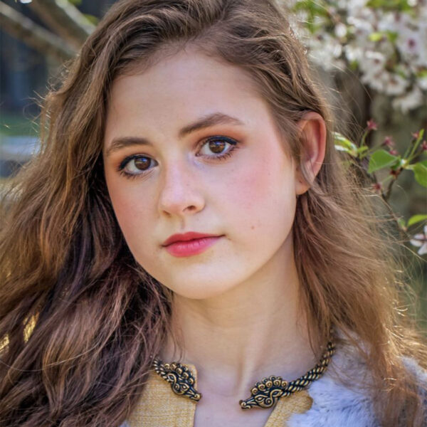 A young girl with long brown hair is striking a pose while wearing a Celtic Stag Neck Torc.