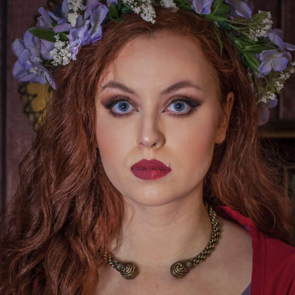 A woman with red hair wearing a flower crown and a Celtic Triskelion Neck Torc.