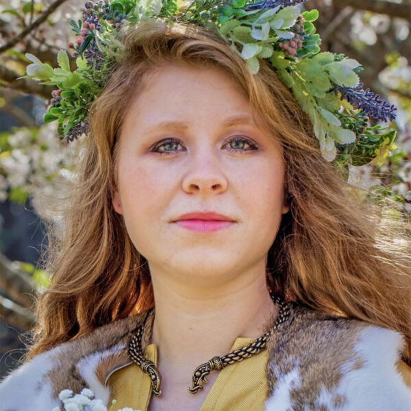 A woman in a viking costume wearing a flower crown and holding onto a Viking Dragon Torc - Heavy Braid.
