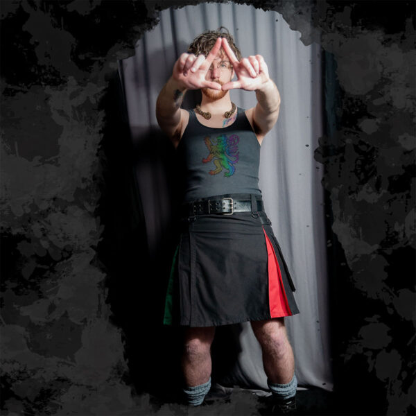 A man wearing a Rainbow Pride Canvas Utility Kilt is posing for the camera.