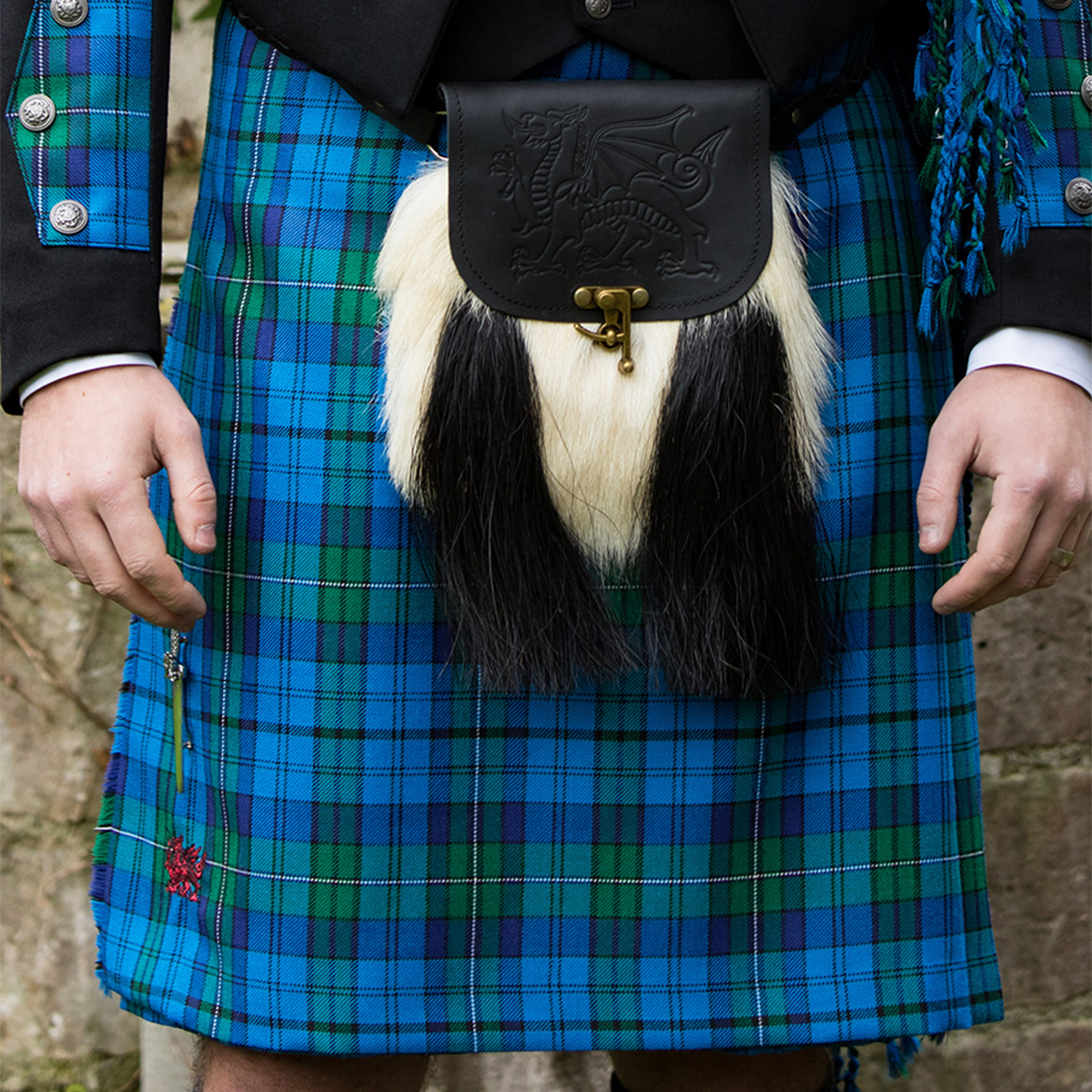 A man wearing a Welsh Tartan 9 Yard Medium Weight Premium Wool Kilt with a fur belt.
