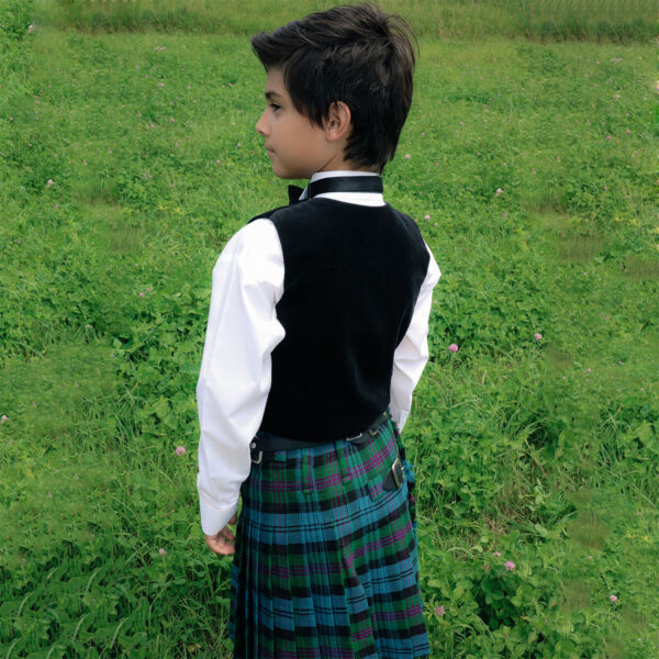 A young boy in a Quality Wool Blend Kilt for Kids standing in a field, wearing a good basic kilt for kids.