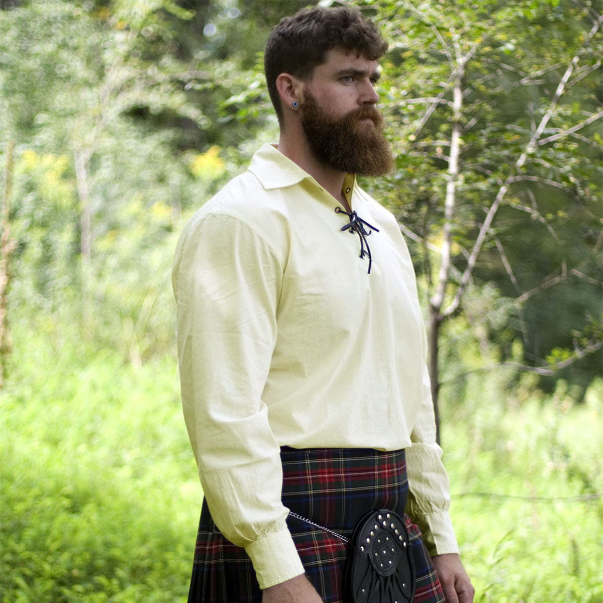 A bearded man in a Traditional Jacobite Kilt Shirt standing in the woods.