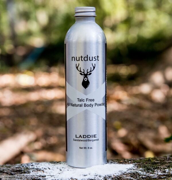 A bottle of Nutdust - Laddie sits on a tree stump.