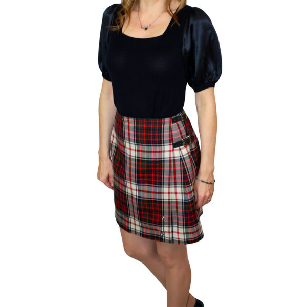 A woman is posing in a plaid skirt.