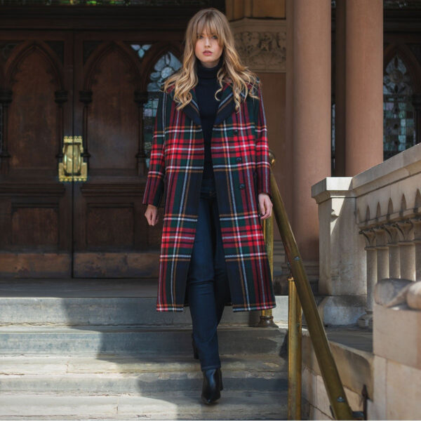 A woman in a red and Scottish Lambswool Eva Peacoat - Stewart Black-NLA 11/21 plaid coat standing on steps.