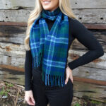 A woman wearing a Welsh Tartan Lambswool Scarf - In-Stock Special.