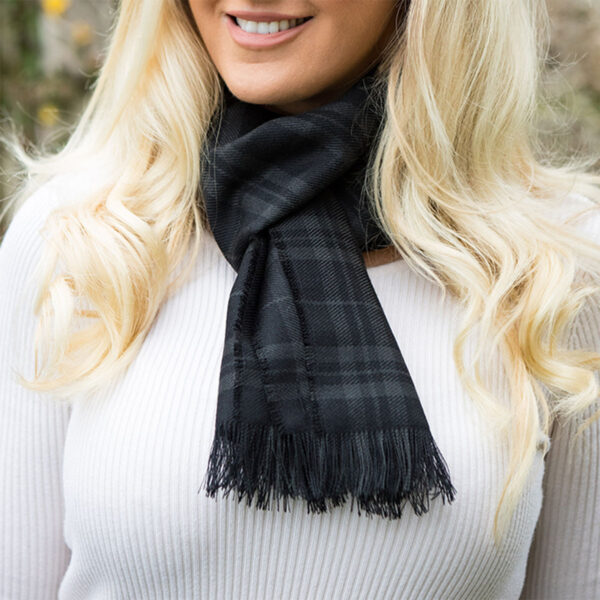 A blonde woman wearing a black plaid Welsh Tartan Scarf Medium Weight Premium Wool.
