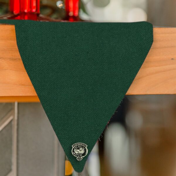 A green triangular scarf hanging on a Reversible Tartan Mantel Runner - Wool Free.