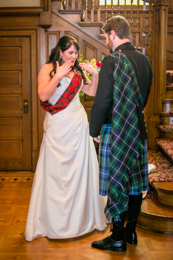 A bride and groom in a kilt, wearing a Light Weight Premium Wool Tartan Sash, standing in front of a staircase.