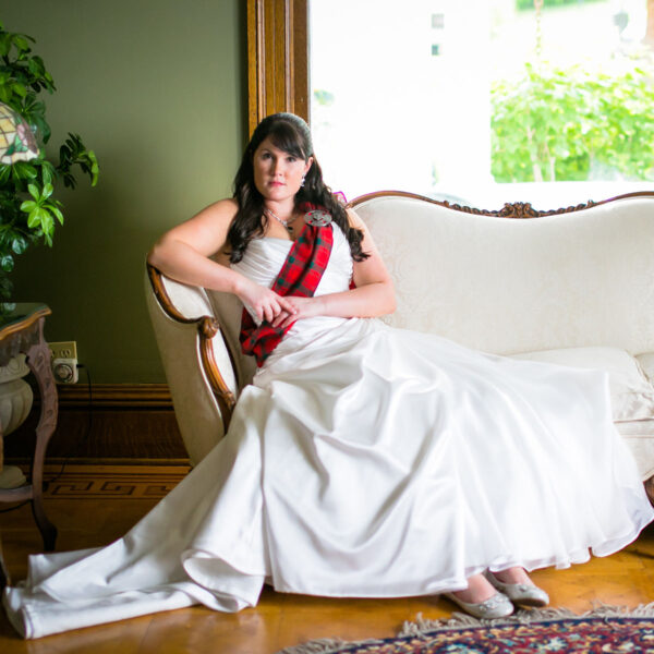 A woman in a wedding dress sitting on a couch.