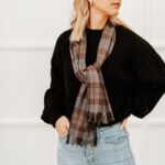 A woman wearing a Tartan Scarf - OUTLANDER Premium Wool - Jamie Fraser Special and black jeans.