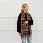 A woman wearing jeans and a plaid scarf, specifically an Tartan Scarf - OUTLANDER Lambswool.
