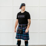 A man in a Quality Wool Blend Kilt with Matching Tartan Flashes and FREE Kilt Hanger standing in front of a white wall.