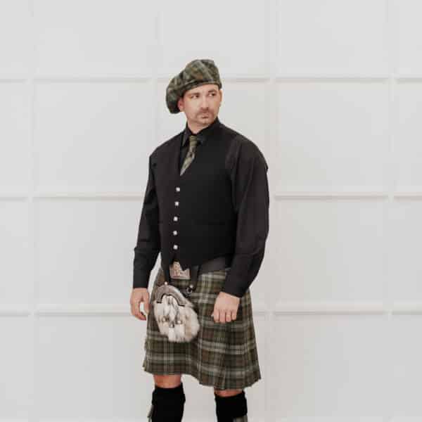 A man in a kilt, wearing Homespun Tartan Neck Ties, standing in front of a white wall.