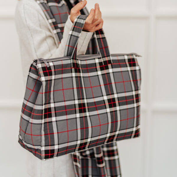 A woman wearing a grey and black plaid tote bag in celebration of National Tartan Day.