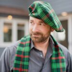 A man wearing a green and red Homespun Wool Blend Tartan Tam beret.