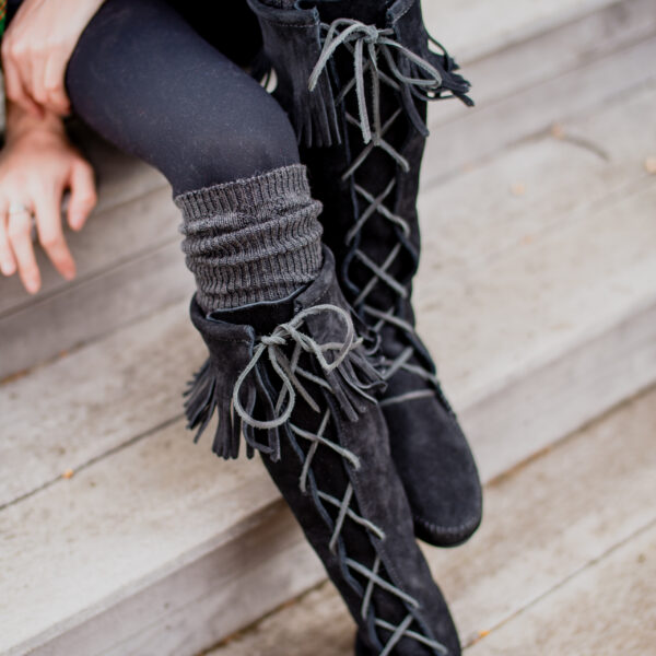 Black thigh high boots with tassels.