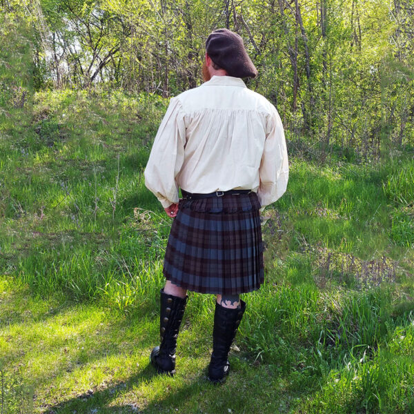 A man in an Outlander Tartan Phillabeg - Homespun Wool Blend standing in a field.