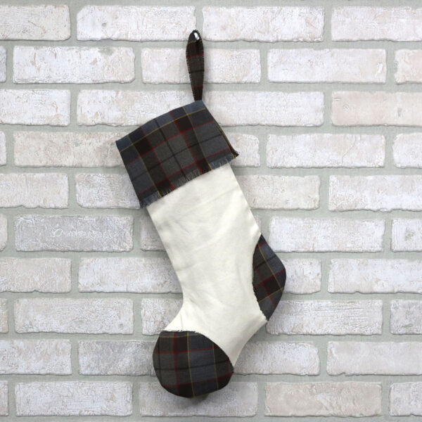 An Outlander Tartan Toes Stocking - Premium 13oz Wool hangs on a brick wall.