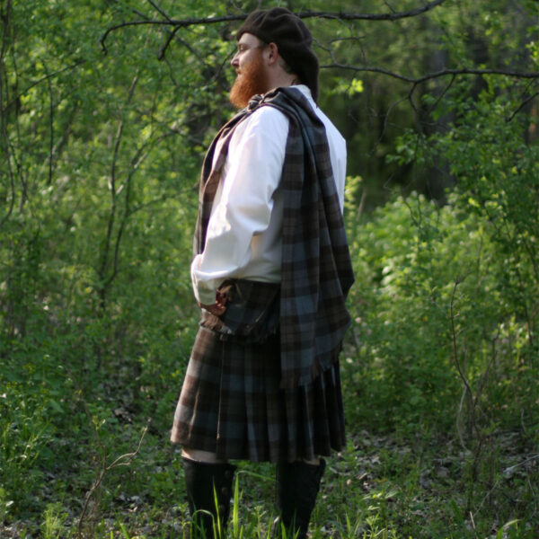 An OUTLANDER Ancient Kilt Authentic Premium Wool Tartan-wearing man standing in the woods.
