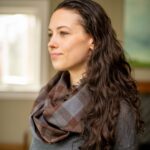 A woman wearing a Tartan Infinity Scarf - OUTLANDER Wool Free in a living room.
