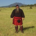 A man in a Welsh Tartan Medium Weight Premium Wool Phillabeg kilt standing in a field.