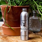 A bottle of Nutdust -Wildling grooming oil next to a potted plant.