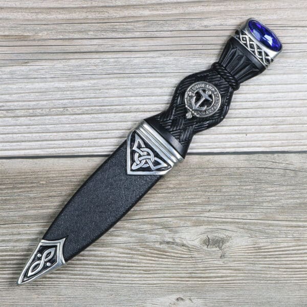 A black Celtic Knot Clan Crest Sgian Dubh knife adorned with a blue stone.