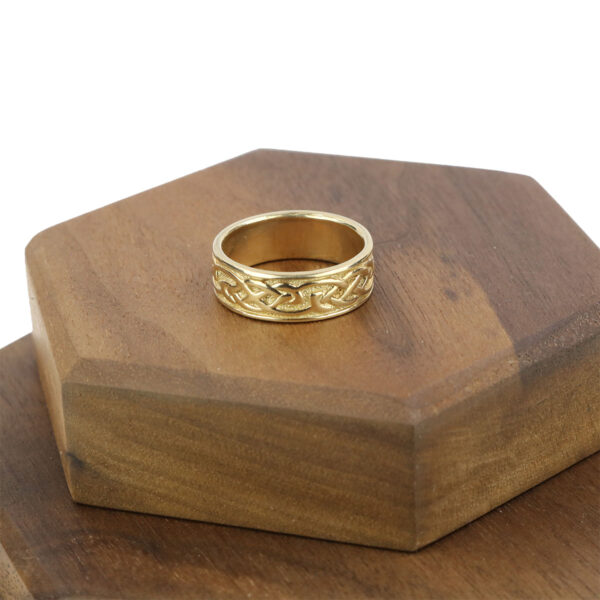 A gold Celtic wedding ring with a Women's 10K Gold Claddagh Wedding Ring - Size 7 design on top of a wooden box.