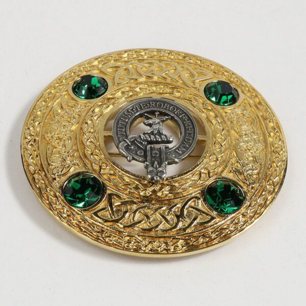 A gold and green brooch with emerald stones.