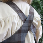 The back of a woman wearing a Tartan Cross Back Apron - Homespun Wool Blend.