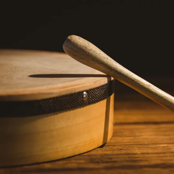 A wooden drum with a wooden stick on a wooden table.