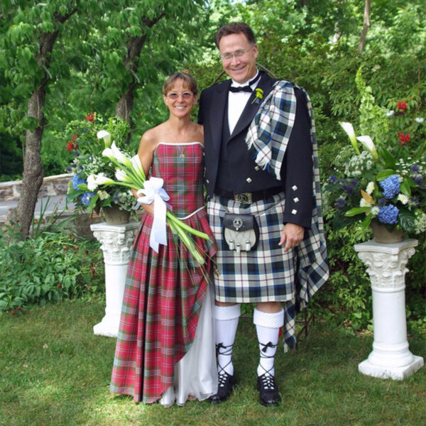 A man in a **kilt** and a woman in a dress, both donning the traditional **Homespun Wool Blend Piper's Plaid** fabric.