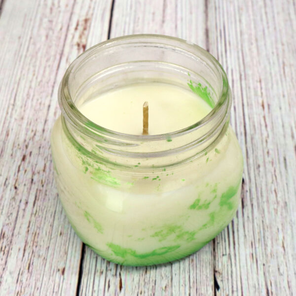 A Homemade Candles in a jar on a wooden table.