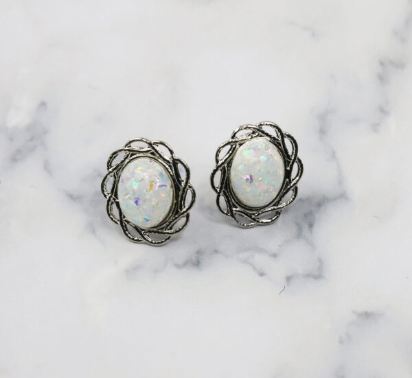 A pair of white Opal Knot stud earrings on a surface.