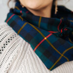 A woman wearing a Tartan Scarf - 13oz Premium Wool with tassels.