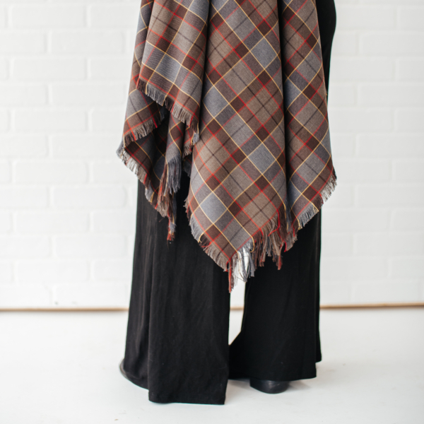 A woman wearing black pants and an OUTLANDER Wrap Premium Lambswool Tartan scarf. (Replace with: OUTLANDER Wrap Premium Lambswool Tartan)